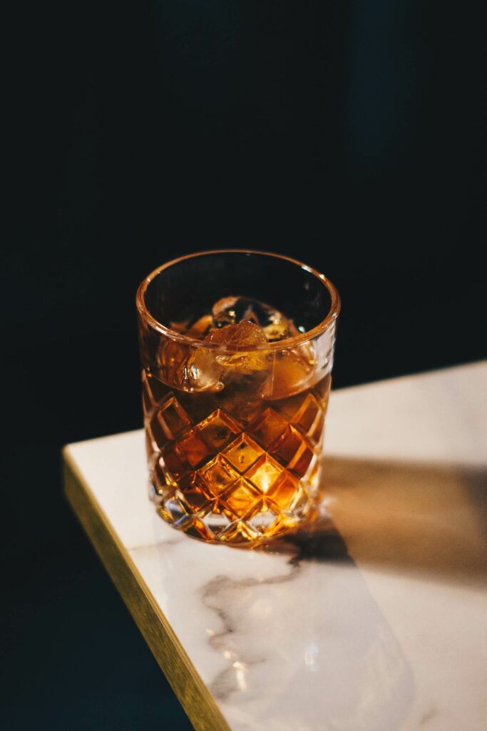 A whisky cocktail sits near the edge of a granite countertop